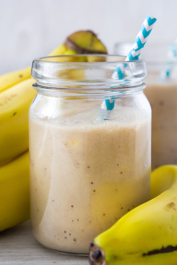 Bananowi smoothies na białym drewnianym tle zdjęcie stock Bananowi smoothies na białym drewnianym tle zdjęcie stock