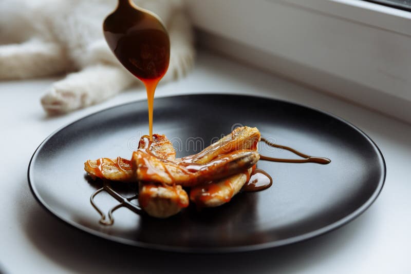 Banană caramelizată artizanală în plăci negre pe masă albă Desert vegetarian. concentrare selectivă royalty free stock images
