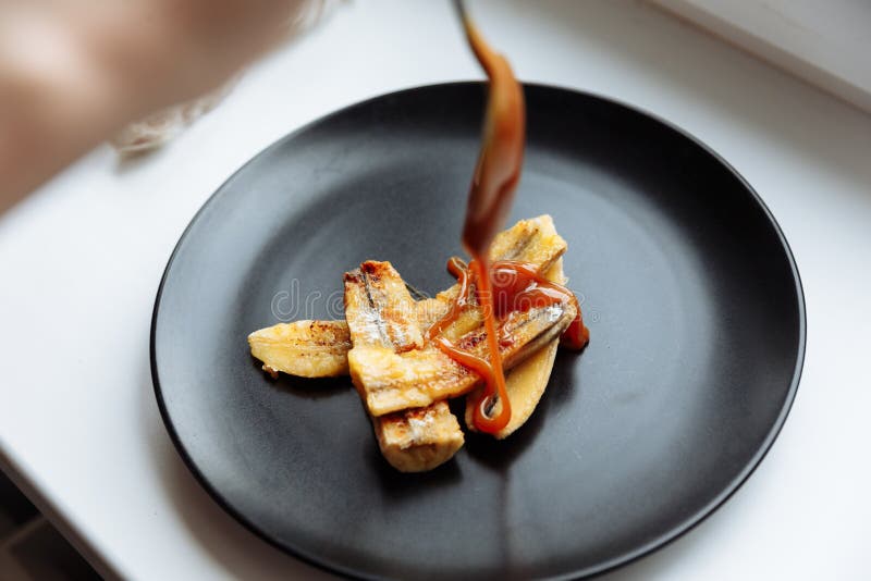 Banană caramelizată artizanală în plăci negre pe masă albă Desert vegetarian. concentrare selectivă royalty free stock image