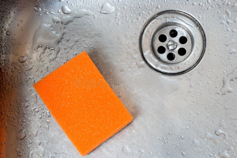Banca da cozinha inoxidável do dreno e esponja alaranjada imagem de stock Banca da cozinha inoxidável do dreno e esponja alaranjada imagem de stock