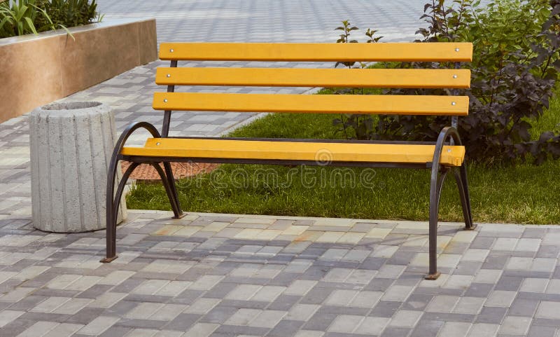 Bancada de madeira amarela e lata de lixo. área de assentos. imagens de stock royalty free