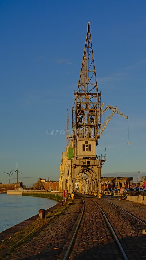 Banchine del porto di Anversa, con le vecchie gru industriali alla luce calda di tramonto fotografie stock Banchine del porto di Anversa, con le vecchie gru industriali alla luce calda di tramonto fotografie stock