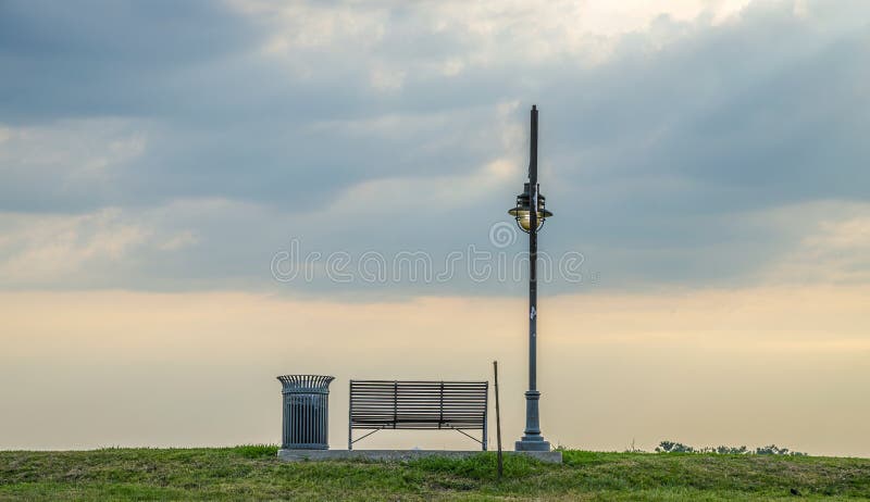 Banco accanto ad un'iluminazione pubblica al tramonto immagine stock libera da diritti Banco accanto ad un'iluminazione pubblica al tramonto immagine stock libera da diritti