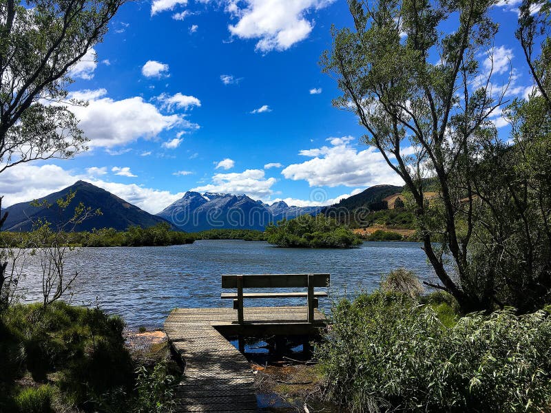 Banco con la vista del lago e della montagna fotografia stock libera da diritti Banco con la vista del lago e della montagna fotografia stock libera da diritti