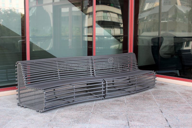 Banco largo del metal que curva para que gente se siente en el edificio exterior foto de archivo