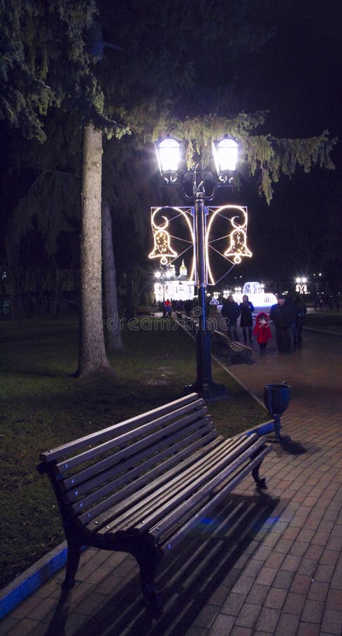 Banco vacío bajo linterna en parque nocturno. las luces de noche iluminan el camino imagen de archivo libre de regalías