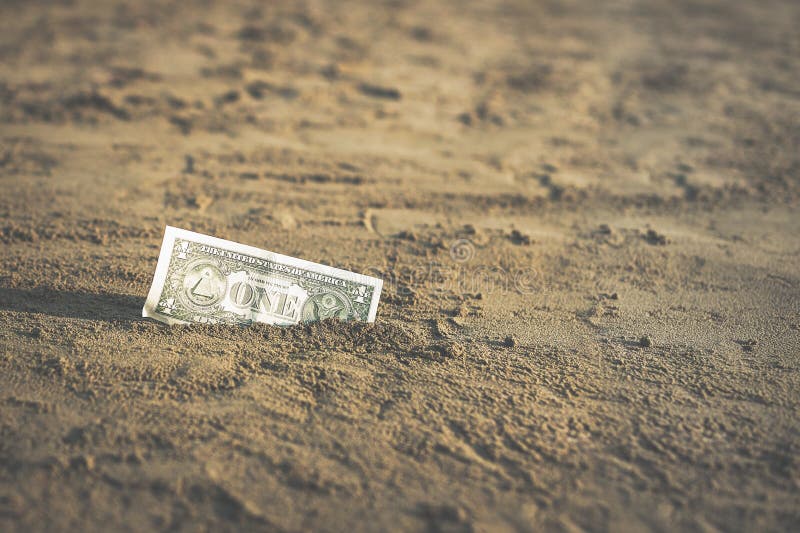 Banconota di un valore di un dollaro nella sabbia sulla spiaggia Concetto del viaggio e della vacanza economici immagine stock libera da diritti Banconota di un valore di un dollaro nella sabbia sulla spiaggia Concetto del viaggio e della vacanza economici immagine stock libera da diritti