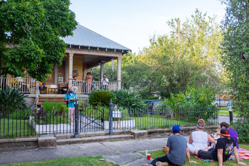 New Orleans, Louisiana/USA - 7/10/2020: Band playing on front porch of house in uptown neighborhood with woman serving watermelon to neighbors. New Orleans, Louisiana/USA - 7/10/2020: Band playing on front porch of house in uptown neighborhood with woman serving watermelon to neighbors