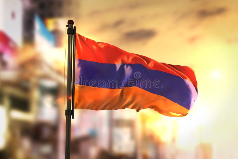 Bandeira de Armênia contra o fundo borrado cidade no nascer do sol Backligh imagem de stock Bandeira de Armênia contra o fundo borrado cidade no nascer do sol Backligh imagem de stock