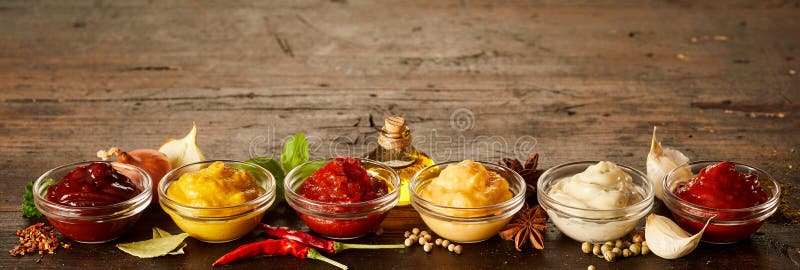 Rustic wood banner with a variety of sauces, dips, marinades and dressings in small glass bowls with ingredients and copy space. Rustic wood banner with a variety of sauces, dips, marinades and dressings in small glass bowls with ingredients and copy space