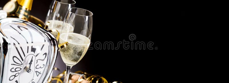 Panoramic banner with New Years champagne sparkling in flutes alongside a bottle on ice and clock counting down to midnight, black background with copy space. Panoramic banner with New Years champagne sparkling in flutes alongside a bottle on ice and clock counting down to midnight, black background with copy space