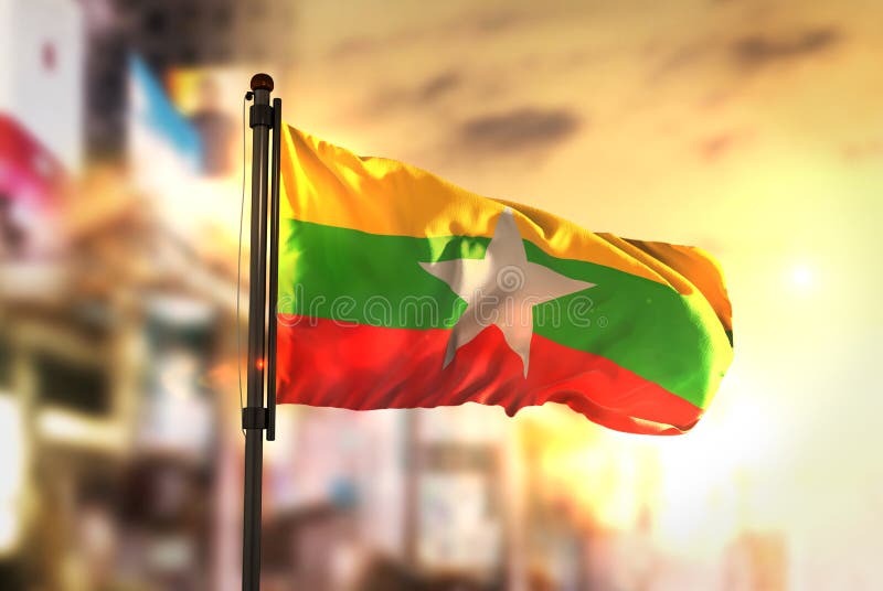 Bandera de Myanmar contra fondo borroso ciudad en la salida del sol Backligh fotos de archivo libres de regalías Bandera de Myanmar contra fondo borroso ciudad en la salida del sol Backligh fotos de archivo libres de regalías