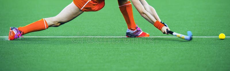 Female athlete field hockey player performing a stretched drag flick on an artificual grass pitch. Female athlete field hockey player performing a stretched drag flick on an artificual grass pitch