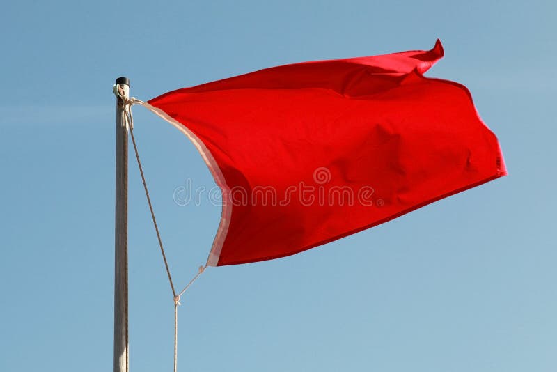Bandera roja que agita sobre el cielo azul