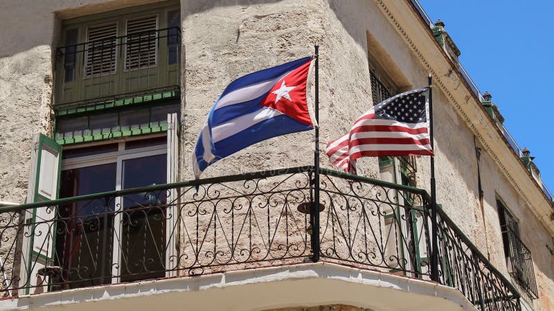 American and Cuban flags are floating on a touristic quarter building. American and Cuban flags are floating on a touristic quarter building.