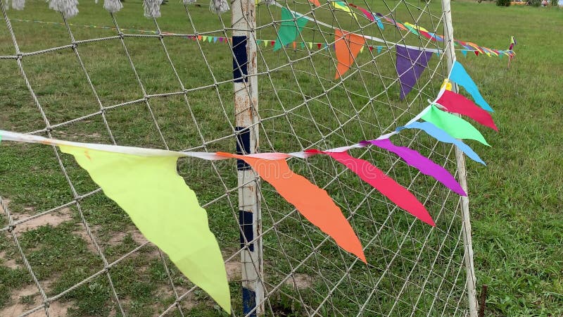 Banderas triangulares coloridas en la cuerda ondeando en el viento en un campo de fútbol cerca de la puerta durante el festival d fotografía de archivo libre de regalías Banderas triangulares coloridas en la cuerda ondeando en el viento en un campo de fútbol cerca de la puerta durante el festival d fotografía de archivo libre de regalías