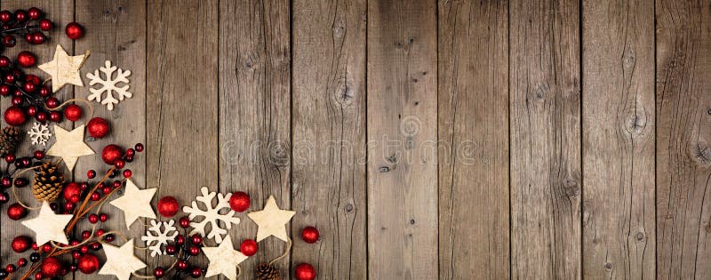 Christmas corner border banner with wood star ornaments and red baubles. Above view on an old wood background. Christmas corner border banner with wood star ornaments and red baubles. Above view on an old wood background