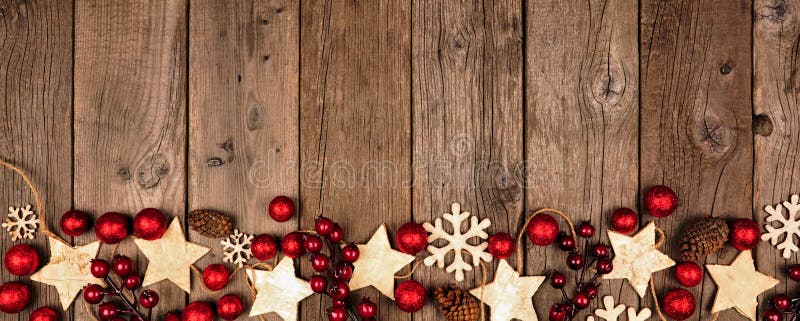 Christmas border banner with wood star ornaments and red baubles. Top view on an old wood background. Christmas border banner with wood star ornaments and red baubles. Top view on an old wood background