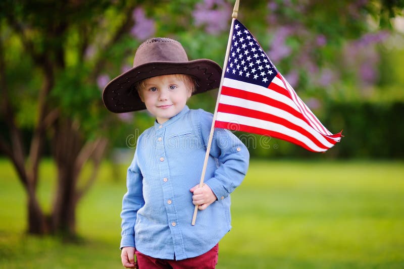 Bandiera americana sveglia della tenuta del ragazzo del bambino in bello parco immagine stock libera da diritti Bandiera americana sveglia della tenuta del ragazzo del bambino in bello parco immagine stock libera da diritti