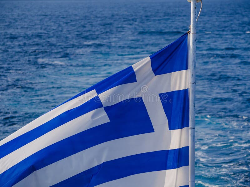 Bandiera greca nel vento e bello mare nei precedenti immagine stock libera da diritti Bandiera greca nel vento e bello mare nei precedenti immagine stock libera da diritti