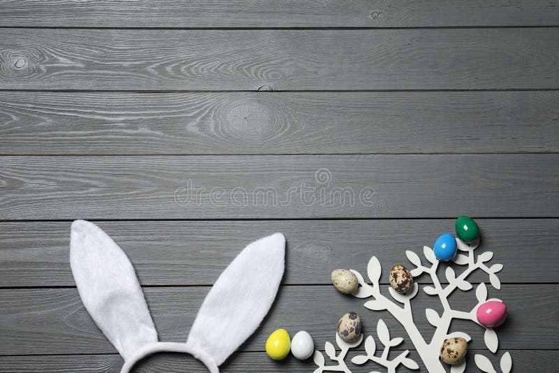 Bandă pentru urechi de iepure de Paști și pom decorativ cu ouă colorate pe fond plat de lemn. stock image
