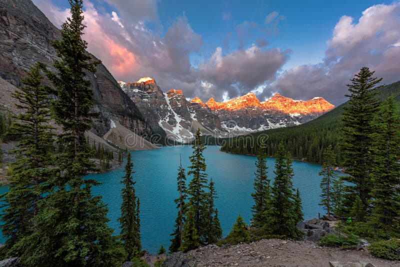 Beautiful sunrise under turquoise waters of the Moraine lake with snow-covered peaks above it in Banff National Park, Rocky Mountains of Canada. Beautiful sunrise under turquoise waters of the Moraine lake with snow-covered peaks above it in Banff National Park, Rocky Mountains of Canada.
