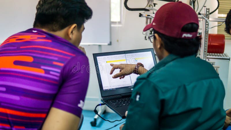 Engineering students discussing and solving the task given on the automation machine system in the laboratory stock photo