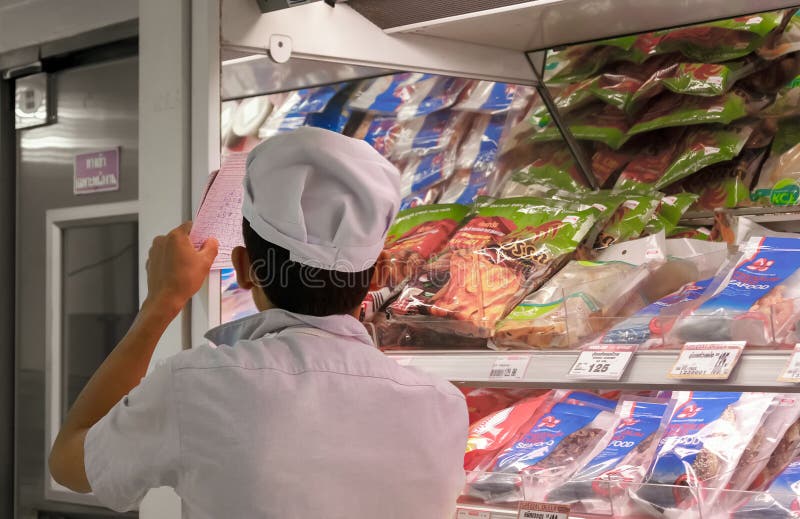 BANGKOK, THAILAND - JULI 16: De supermarktbediende controleert inventaris binnen bij de gekoelde sectie van Foodland-supermarkt stock afbeeldingen BANGKOK, THAILAND - JULI 16: De supermarktbediende controleert inventaris binnen bij de gekoelde sectie van Foodland-supermarkt stock afbeeldingen