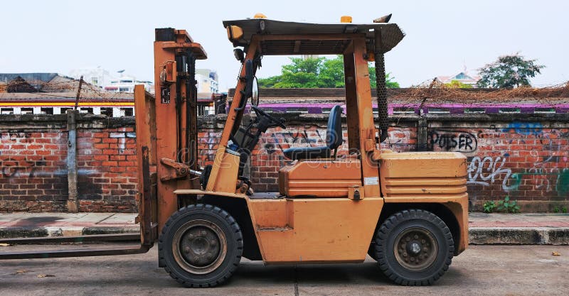 Industrial Forklift Parked in Front of Brick Wall Editorial Photo