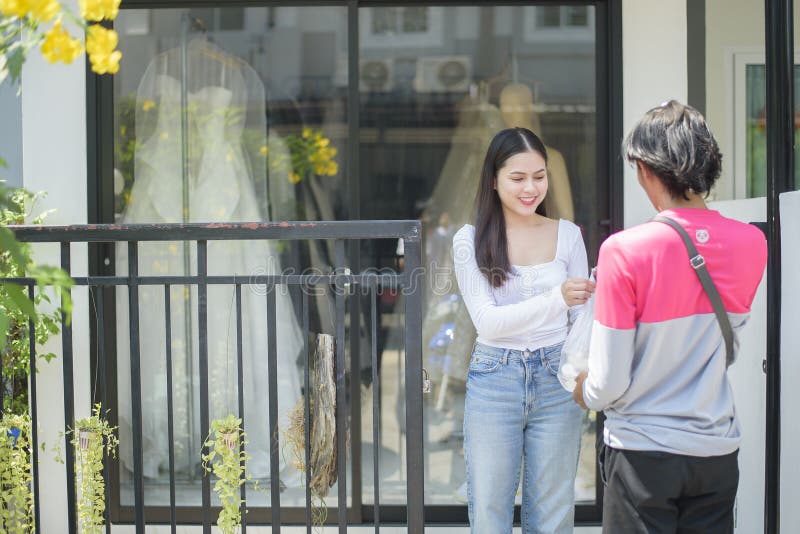 Bangkok, Thailand  - 28 march 2020; A woman is getting food from foodpanda delivery man in front of the house
