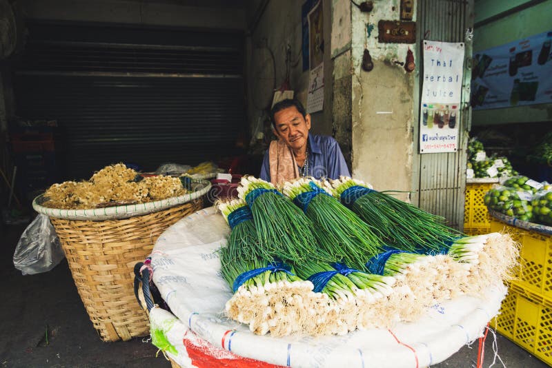 Bangkok, Thailand - M?rz 2019: Mann, der Fr?hlingszwiebel am Stra?enmarkt verkauft stockfotografie Bangkok, Thailand - M?rz 2019: Mann, der Fr?hlingszwiebel am Stra?enmarkt verkauft stockfotografie