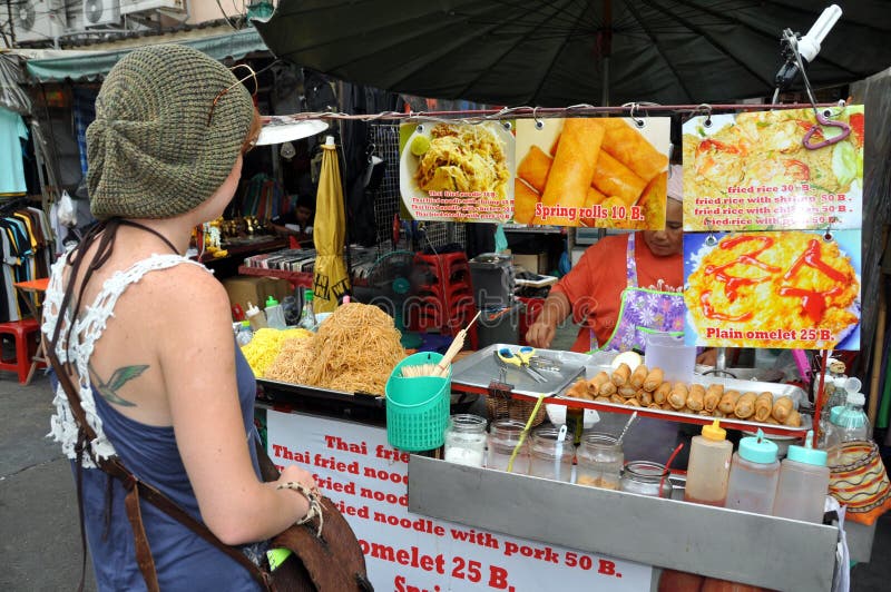 Bangkok, Thailand: Street Food Vendor. A tourist stops to buy delicious Thai street food from a vendor on famed Khao San Road in Bangkok, Thailand stock image Bangkok, Thailand: Street Food Vendor. A tourist stops to buy delicious Thai street food from a vendor on famed Khao San Road in Bangkok, Thailand stock image