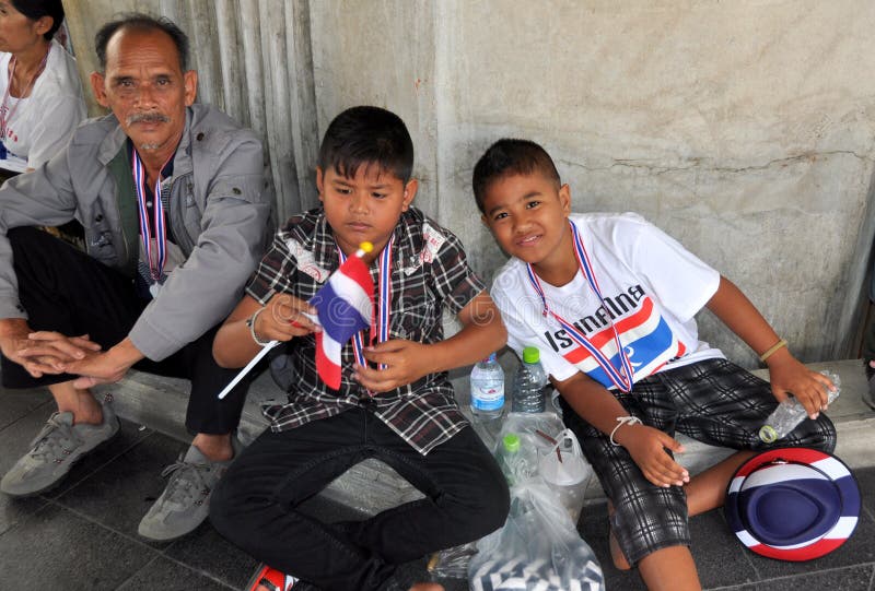 Two young boys with patriotic Thai flags, hats, and whistle necklaces at the Operation Shut Down Bangkok anti-government demonstration on 13 January 2014 in Bangkok, Thailand. Two young boys with patriotic Thai flags, hats, and whistle necklaces at the Operation Shut Down Bangkok anti-government demonstration on 13 January 2014 in Bangkok, Thailand.