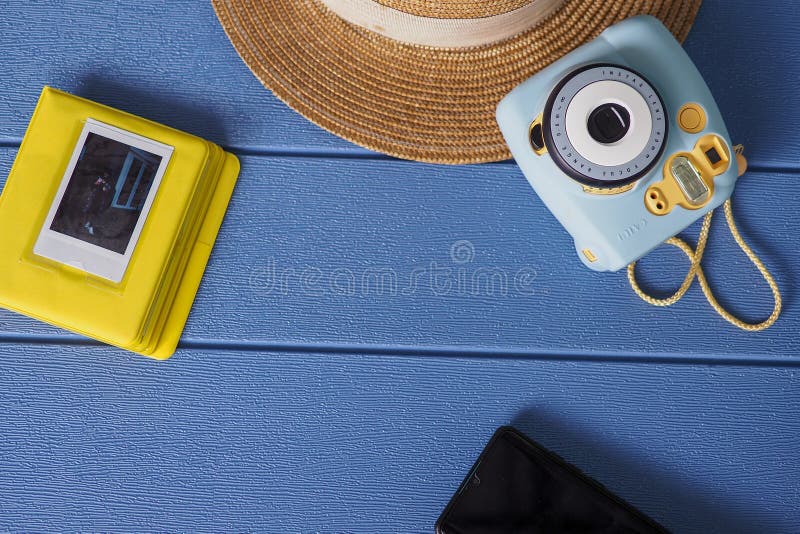 Fujifilm Instax mini 8 instant camera on blue background with hat and smartphone