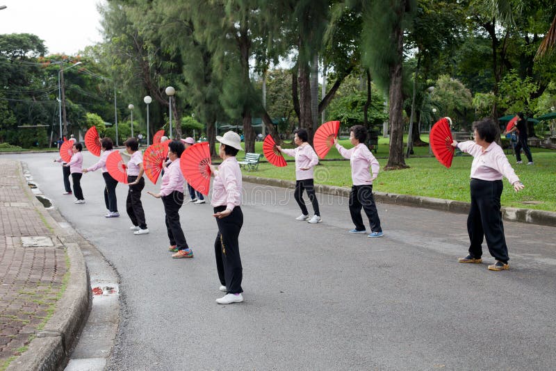 BANGUECOQUE TAILÂNDIA - grupo de Oct17- da dança da mulher adulta com o fã chinês para o exercício no coração do parque público de foto de stock BANGUECOQUE TAILÂNDIA - grupo de Oct17- da dança da mulher adulta com o fã chinês para o exercício no coração do parque público de foto de stock