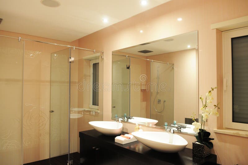 Bathroom in a light pink, with roses drawn in the wall. Glazed cabine shower, with double sinks in white ceramic and mirror. White orchid on a vase. Bathroom in a light pink, with roses drawn in the wall. Glazed cabine shower, with double sinks in white ceramic and mirror. White orchid on a vase.