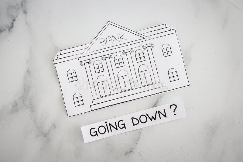 Insolvency and banks closing down concept, bank made of paper with Going Down ? caption underneat royalty free stock photo Insolvency and banks closing down concept, bank made of paper with Going Down ? caption underneat royalty free stock photo