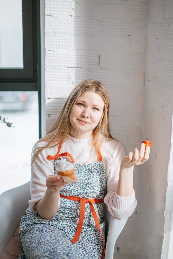 Banketbakkersvrouw in gevlekte schort die haar ejoying enkel gebakken cupcake met strauberry stock foto's Banketbakkersvrouw in gevlekte schort die haar ejoying enkel gebakken cupcake met strauberry stock foto's