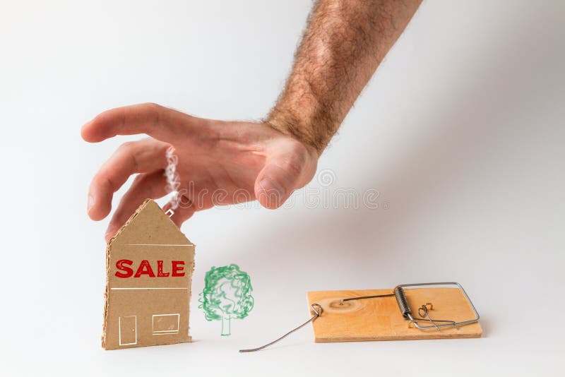 Bankinvestitionen und Hypotheken. männliche Hand, die nach dem neben der Falle liegenden Kartonhaus greift. Textverkauf. weißer Hi lizenzfreies stockbild