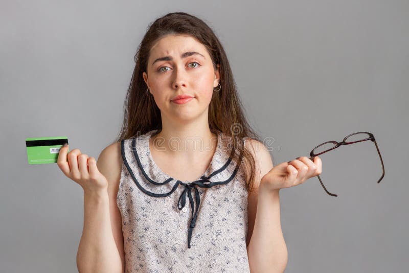 Bankinvestitionen und -karten Eine junge Frau in einer Bluse, die eine Bankkarte und eine Brille in der Hand hält, verwirrt, ihre stockfotos Bankinvestitionen und -karten Eine junge Frau in einer Bluse, die eine Bankkarte und eine Brille in der Hand hält, verwirrt, ihre stockfotos