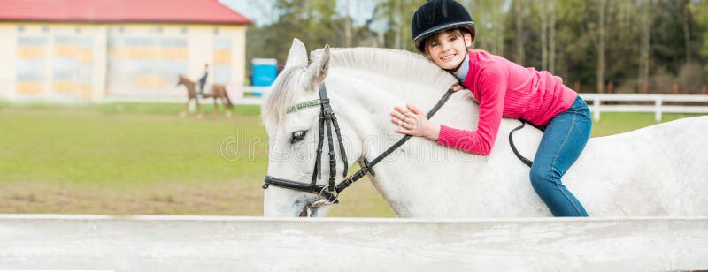 Banner beautiful brunette girl kissing her horse. A sweet girl riding a white horse, an athlete engaged in equestrian sports. Banner beautiful brunette girl kissing her horse. A sweet girl riding a white horse, an athlete engaged in equestrian sports