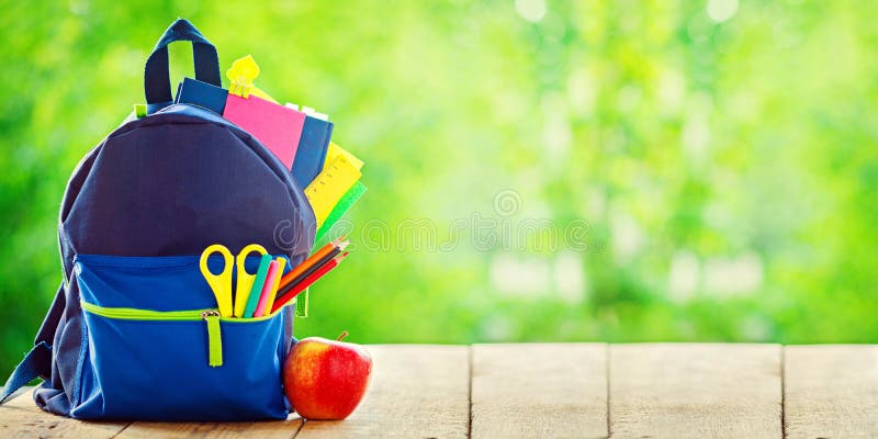 Banner. Full School backpack with apple on wooden and nature green background. royalty free stock image