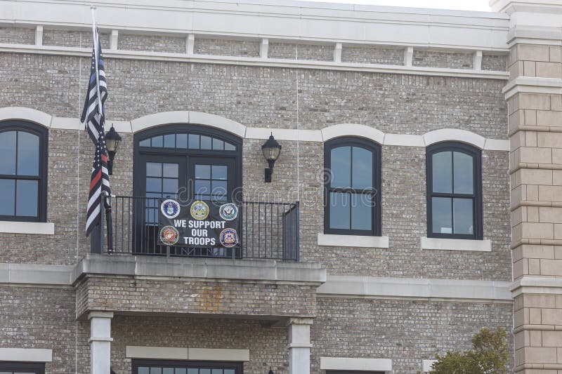 Suwanee, GA USA - August 4, 2023: A banner that says "We support our troops" and firefighter and law enforcement flags hang from a condo balcony, on August 4, 2023 in Suwanee, GA. Suwanee, GA USA - August 4, 2023: A banner that says "We support our troops" and firefighter and law enforcement flags hang from a condo balcony, on August 4, 2023 in Suwanee, GA.