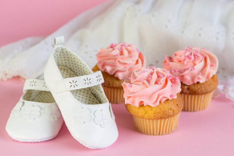 Baptism or birthday girl invitation with pink cup cakes and whit. E shoes on pink background stock photo Baptism or birthday girl invitation with pink cup cakes and whit. E shoes on pink background stock photo