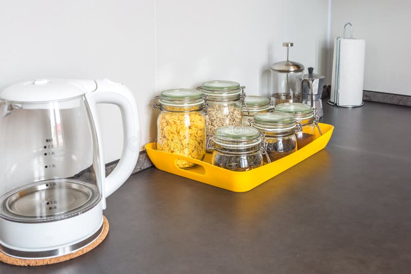 Barattoli d'annata alla moda di vetro con alimento e la teiera differenti nell'interno della cucina moderna in appartamento piano fotografia stock libera da diritti Barattoli d'annata alla moda di vetro con alimento e la teiera differenti nell'interno della cucina moderna in appartamento piano fotografia stock libera da diritti