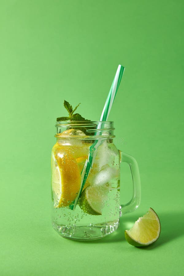 Barattolo di muratore con il mojito ackoholic scintillante con ghiaccio, fette di calce e limone, foglia della menta con le pagli fotografia stock libera da diritti Barattolo di muratore con il mojito ackoholic scintillante con ghiaccio, fette di calce e limone, foglia della menta con le pagli fotografia stock libera da diritti