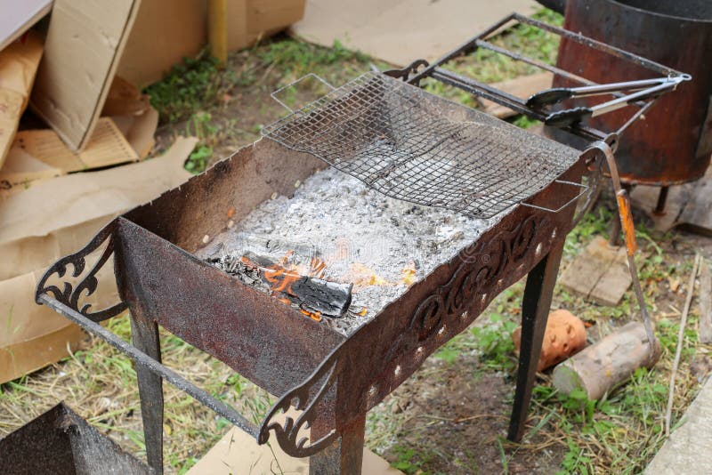 barbecue and burning wood. fire and ashes in the grill. forged grill in the yard on the grass