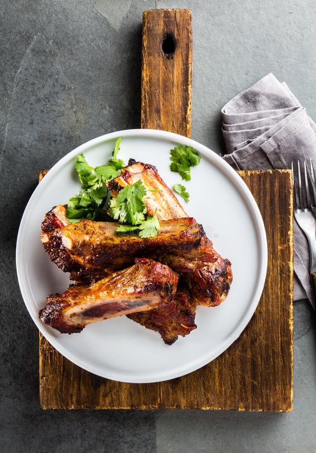 Barbecue pork ribs served on wite plate, top view