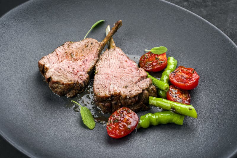 Barbecue rack of lamb neck with paprika and tomato on a modern design plate. Barbecue rack of lamb neck with paprika and tomato offered as close- up on a modern royalty free stock photography Barbecue rack of lamb neck with paprika and tomato on a modern design plate. Barbecue rack of lamb neck with paprika and tomato offered as close- up on a modern royalty free stock photography