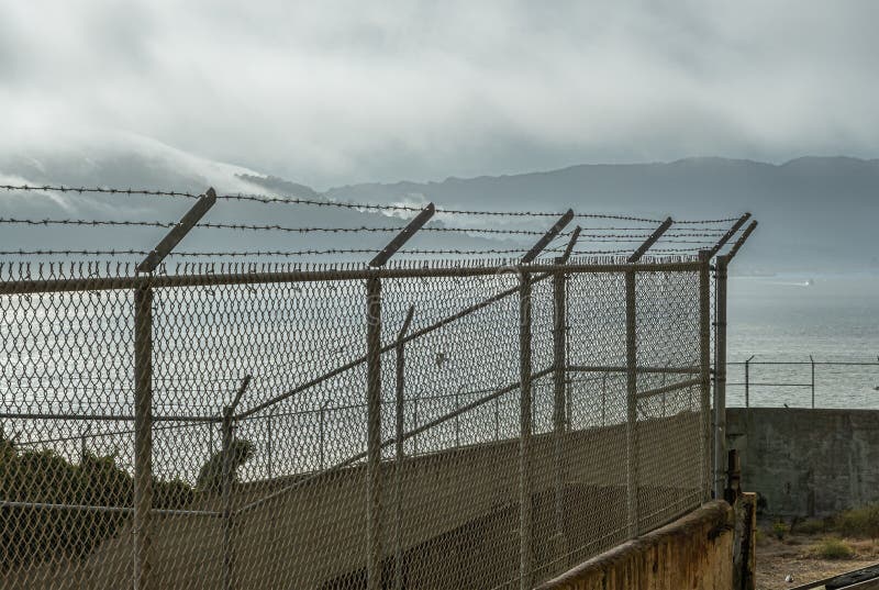 San Francisco, CA, USA - July 12, 2023: Inside historic Alcatraz prison. Barbed wire heavy fence around small airing space outside meeting room. San Francisco, CA, USA - July 12, 2023: Inside historic Alcatraz prison. Barbed wire heavy fence around small airing space outside meeting room